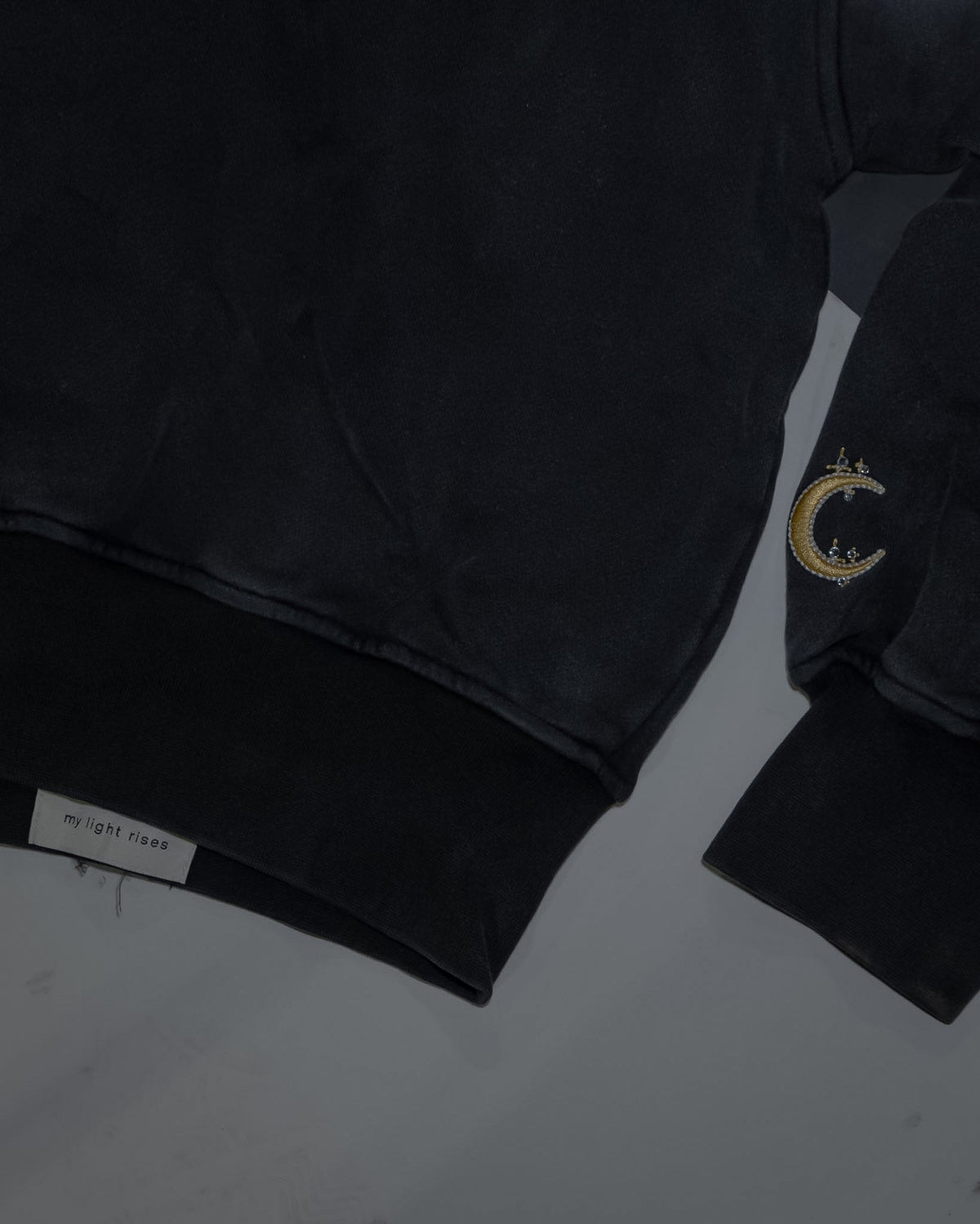 The cuff and hem of the Dawn zip-up, gold crescent embroidery