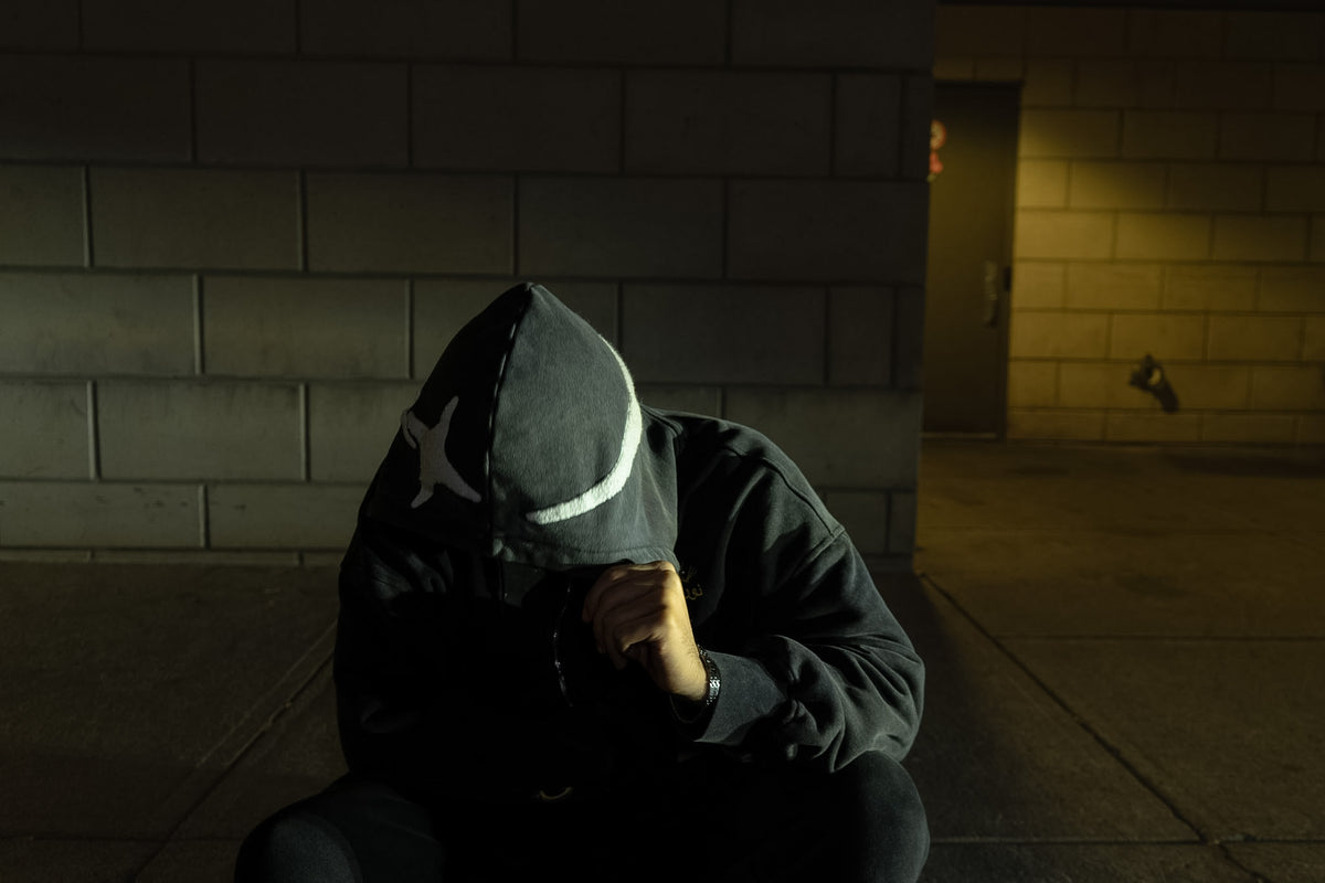A figure crouched at night, hood up, the star appliqué catching the light