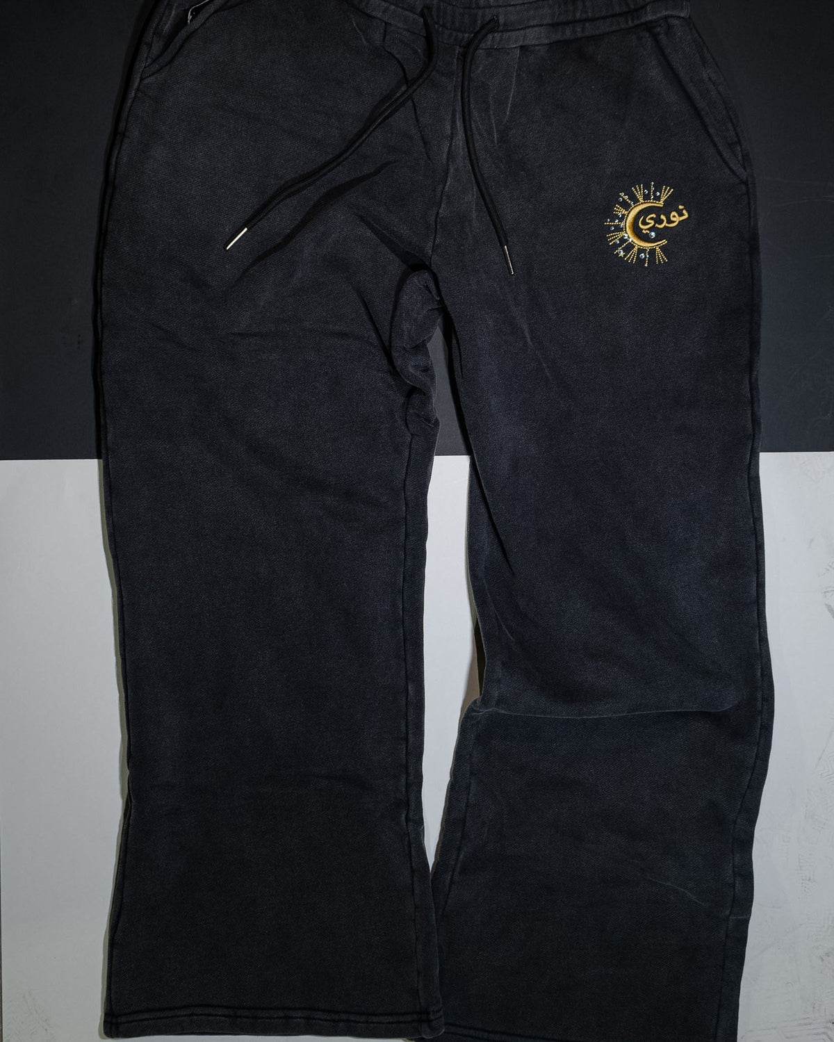 The Dawn flared sweatpant at full length, gold نوري embroidery at the thigh